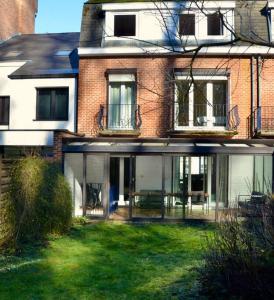 une grande maison en briques avec une pelouse devant elle dans l'établissement Appart 8 pers 10' à pied du centre:Le Savoie Namur, à Namur