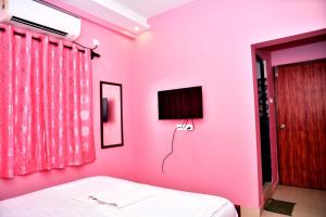 a pink bedroom with a bed and a tv at INDRAYANI GUEST HOUSE in Calangute
