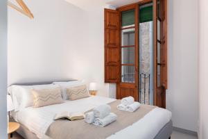 Un dormitorio con una cama blanca con toallas. en Flateli Cort Reial 10, en Girona