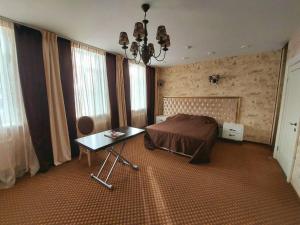 een slaapkamer met een bed en een tafel en ramen bij Hotel Onegin in Stavropol
