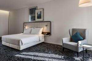 une chambre d'hôtel avec un lit et une chaise dans l'établissement Radisson Hotel & Apartments Dammam Industry City, à Dammam