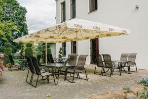 un groupe de tables et de chaises sous un parapluie dans l'établissement Hotel Metsis, à Valga