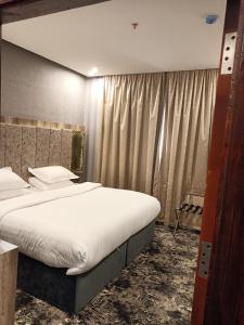 una camera da letto con un grande letto con lenzuola bianche di حياة تاون البدع a Al Bad‘