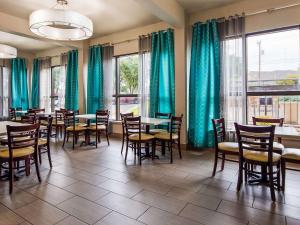 un comedor con mesas, sillas y cortinas verdes en Clarion Pointe near Medical Center, en San Antonio