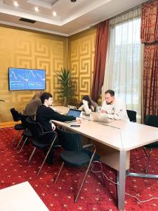 un groupe de personnes assises à une table avec des ordinateurs portables dans l'établissement Ark Palace Hotel & SPA, à Odessa