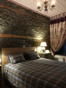 1 dormitorio con cama y pared de piedra en Δάφνη 1933, Λιθόχτιστο Αρχοντικό στο Βουνό, en Ano Chora