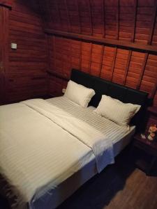 - un lit avec des draps et des oreillers blancs dans l'établissement Les chalets Uluwatu, à Uluwatu