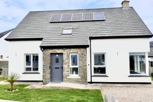 a white house with solar panels on the roof at The Palm, Cnoc na Gaoithe, Dunfanaghy in Dunfanaghy