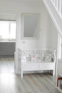 a white living room with a bench with pillows on it at The Palm, Cnoc na Gaoithe, Dunfanaghy in Dunfanaghy