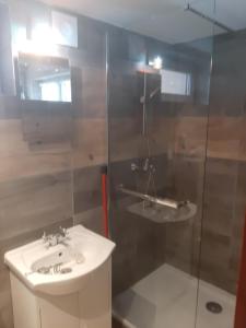 a bathroom with a sink and a glass shower at Garsoniera SOWA in Polanica-Zdrój