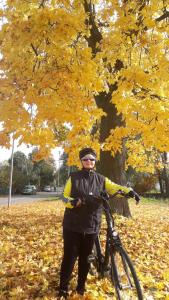 a person standing next to a bike in front of a tree at Garsoniera SOWA in Polanica-Zdrój