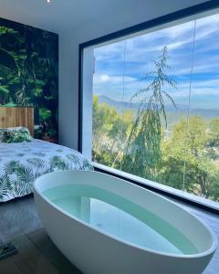 eine Badewanne in einem Schlafzimmer mit einem großen Fenster in der Unterkunft Petit Mirador in Torrelles de Llobregat