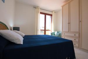 a bedroom with a blue bed and a window at SardegnaSummer Il Borgo Porto San Paolo in Porto San Paolo