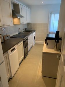 a kitchen with white cabinets and a stove top oven at Comfy flat in the heart of St Leonards in St. Leonards