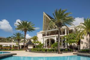 un complejo con piscina y palmeras en The Residence Mauritius en Belle Mare