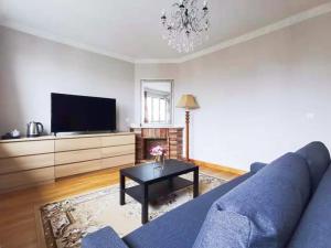 a living room with a blue couch and a tv at La Maison Charentonneau in Maisons-Alfort