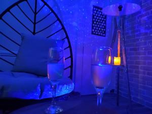 two wine glasses sitting on a table with a lamp at Jacuzzi privatif dans maison de village au calme in Flaviac