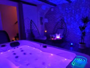 eine Badewanne in einem Zimmer mit blauen Lichtern in der Unterkunft Jacuzzi privatif dans maison de village au calme in Flaviac