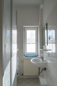 a white bathroom with a sink and a window at Ferienwohnung 1, Waldesruh Dierhagen in Dierhagen