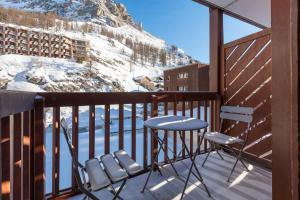 Un balcón con 2 sillas, una mesa y una montaña en Résidence Le Val d'Illaz - Val-d’Isère en Val dʼIsère