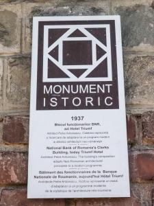 ein Schild an einer Backsteinmauer mit einem monumentalen Stein in der Unterkunft Hotel Triumf in Bukarest