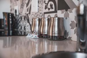 a row of metal coffee pots sitting on a counter at Harbour Cottages, Humewood in Port Elizabeth
