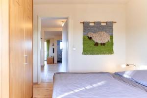 a bedroom with a bed and a painting of a sheep on the wall at Seestern in Nordstrand