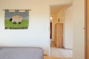 a bedroom with a bed and a painting of a sheep at Suedwind in Nordstrand
