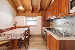 a kitchen with wooden cabinets and a table with a sink at Casa Nicoletta inverno in Livigno +15 photos