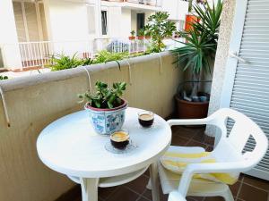 uma mesa branca e cadeiras numa varanda com uma planta em Captains Jack Home em Sitges
