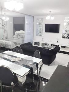 a living room with a black couch and a bed at Apartament Glamour in Gniezno