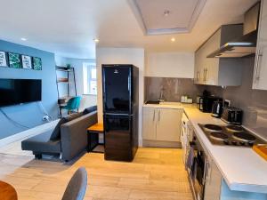 a kitchen and living room with a refrigerator and a couch at New Refurb Top Floor Flat in Central Cheltenham in Cheltenham