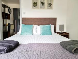 a bedroom with a large bed with blue pillows at New Refurb Top Floor Flat in Central Cheltenham in Cheltenham