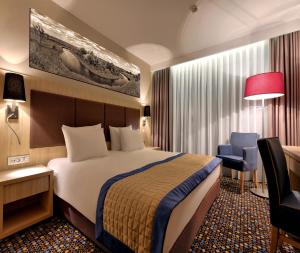 ブスコ・ズドロイにあるブリストル アート＆メディカル スパのベッド、デスク、椅子が備わるホテルルームです。