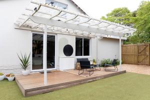 a pergola over a deck with chairs and a table at Peaceful Modern Home with Private Garden in Durban North in Durban