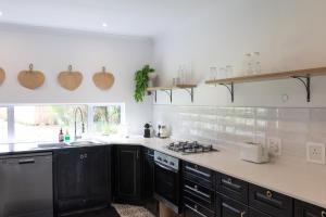 a kitchen with black cabinets and a white counter top at Peaceful Modern Home with Private Garden in Durban North in Durban +9 photos
