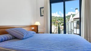 - une chambre avec un lit bleu et une vue sur un balcon dans l'établissement 1Kim01 - Llafranc, à Llafranc