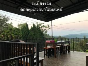 a table and chairs on a balcony with a view at ดอยตุงเฮงธนาโฮมสเตย์ in Ban I-Ko Pa Kluai