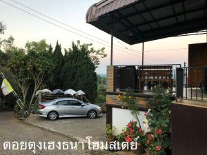 a car parked in a parking lot next to a house at ดอยตุงเฮงธนาโฮมสเตย์ in Ban I-Ko Pa Kluai