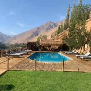 a swimming pool with lounge chairs and mountains in the background at Cabañas Miraelqui in Pisco Elqui