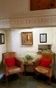 twee stoelen met rode kussens naast een tafel bij The Crown House Inn in Great Chesterford