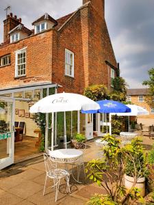 two tables and umbrellas in front of a building at The Crown House Inn in Great Chesterford