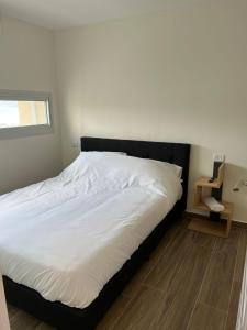 a bedroom with a white bed with a black headboard at מגדל חי in Eilat