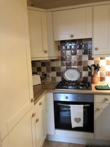 a kitchen with white cabinets and a stove top oven at Beautiful riverfront cosy one bedroom apartment in Upton upon Severn