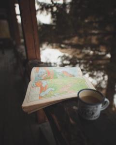 een boek en een kopje koffie op een tafel bij 4 Mountains Hotel in Bystrets