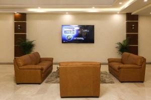 una sala de espera con 2 sillas y TV de pantalla plana en The M Suite, en Juffair