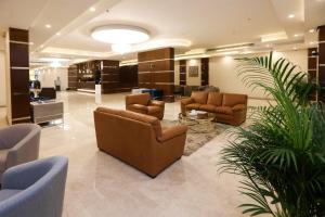 a lobby with couches and chairs and a plant at The M Suite in Juffair