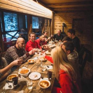 a group of people sitting around a table eating food at 4 Mountains Hotel in Bystrets