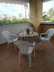 einen Tisch und Stühle in einem Zimmer mit Fenstern in der Unterkunft Primera linea de playa Punta del Moral El Espigon in Ayamonte