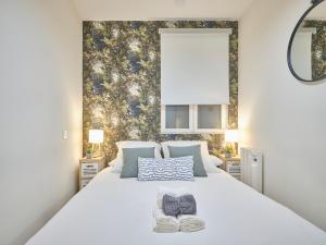 ein weißes Bett mit einem Paar Schuhe darauf in der Unterkunft NEW Retiro recién reformado 10 min en metro a Sol, hasta seis personas in Madrid